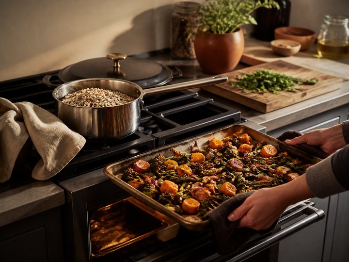 A tray of vegetables and a saucepan of grains in a compact kitchen